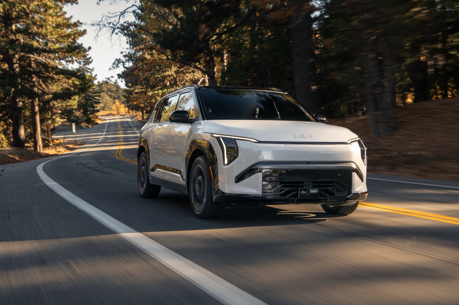 Conducción del SUV eléctrico compacto Kia EV3 2027 blanco, vista frontal de tres cuartos