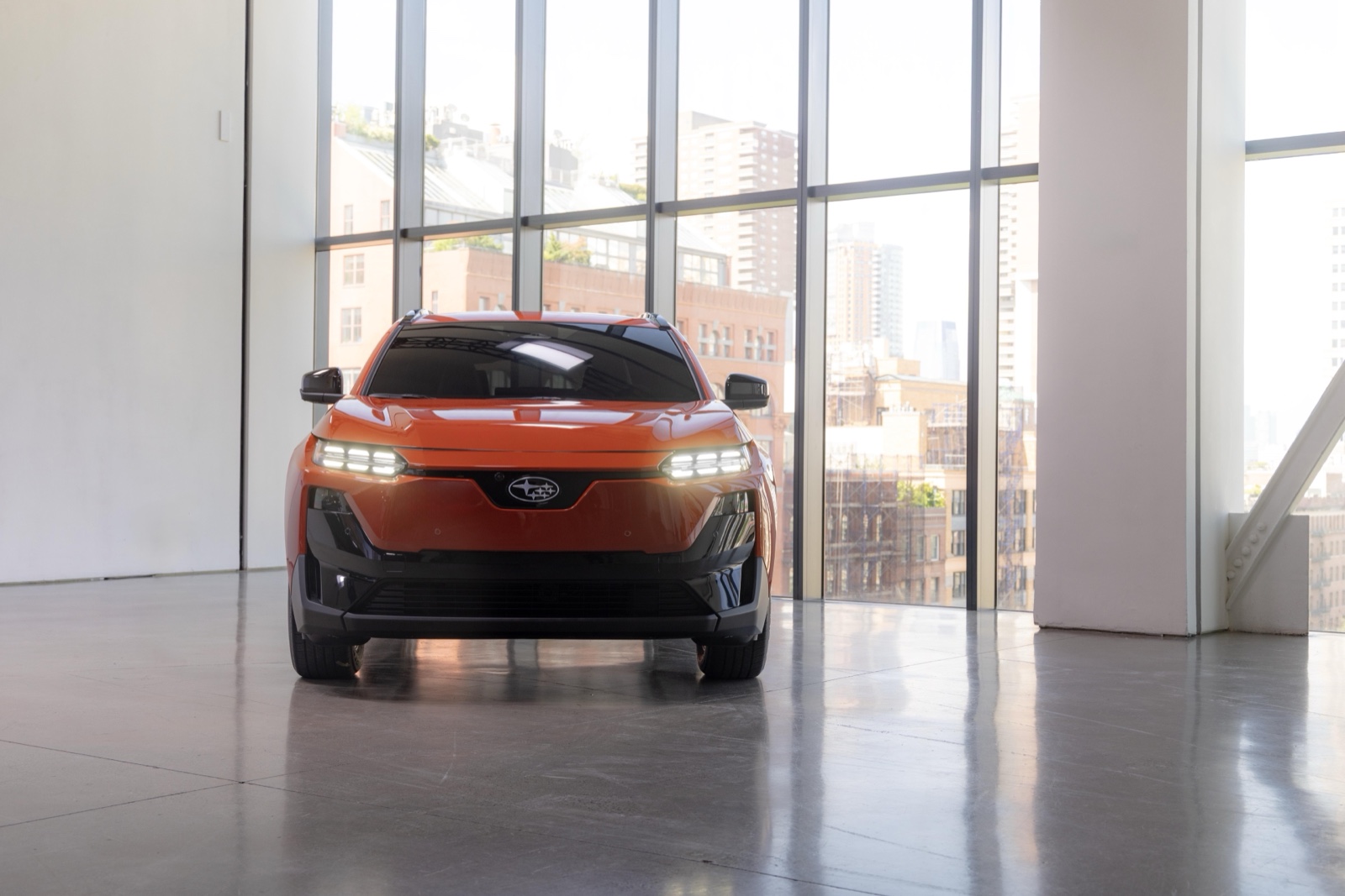 Subaru Uncharted EV 2026 naranja con el horizonte de Nueva York detrás de un vidrio